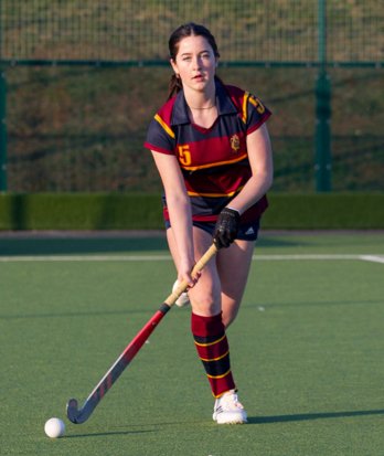 Hockey player dribbling the ball on their stick on the Astroturf