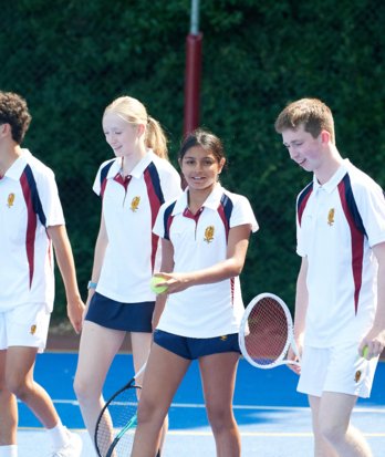 Pupils holding rackets and balls and walking down the Tennis Court