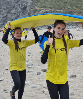 Year 8 Prep School pupils carrying surfboards in wetsuits on a trip to Cornwall