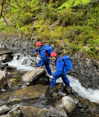 Prep School pupils hiking up rocks next to a river on a trip to Snowdonia