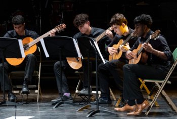  Pupils playing their guitars on stage as part of a concert 