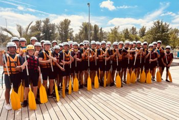  Pupils in life jackets and helmets holding paddles ready to go kayaking 