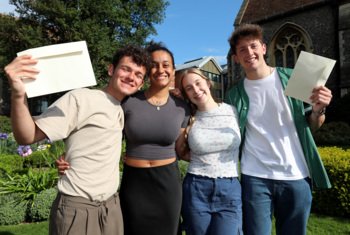  Soames Scholars holding their A-Level results envelopes and looking happy together 