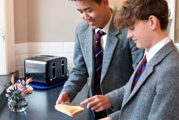  Boarders spreading jam onto toast in the kitchen at break time 