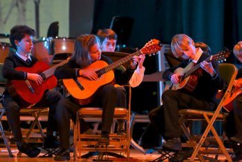  Prep School pupils performing a piece on the guitar as a group as part of a concert in the Hall 