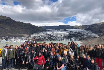  Geography pupils standing in front of a glacier on a trip to Iceland 