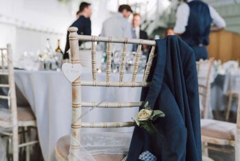  Groom's jacket on the back of his seat at his wedding reception 