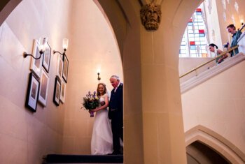  Bride and her father walking down the stairs together on her wedding day 