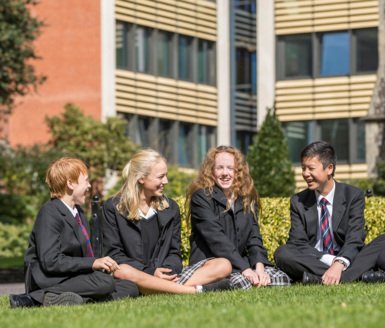  Pupils sitting in the Quad talking to each other sitting on the grass in the Quad 