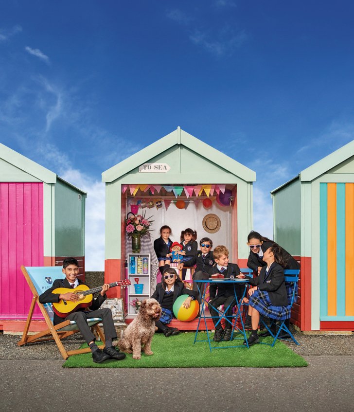  Prep-School pupils playing together in a beach hut on Brighton seafront on a sunny day 