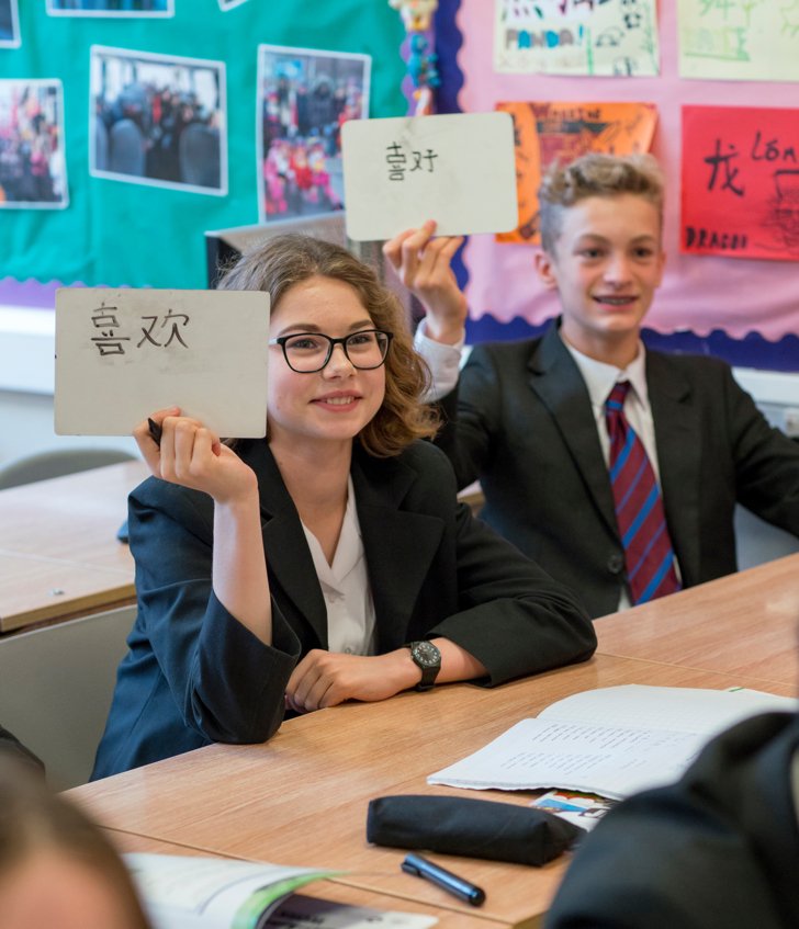  Pupils holding whiteboard with Mandarin characters written on them in a lesson 