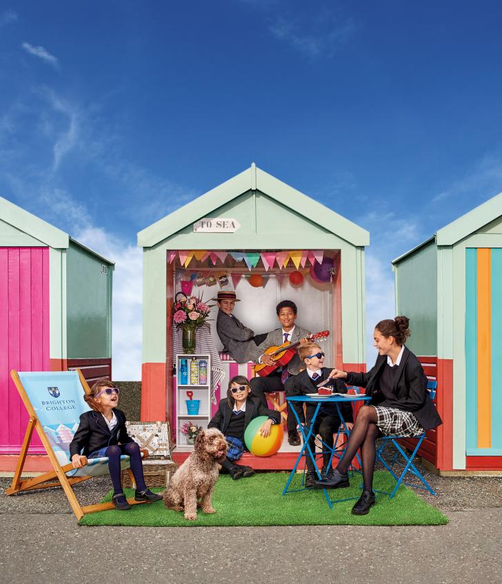  Prep-School pupils playing together in a beach hut on Brighton seafront on a sunny day 