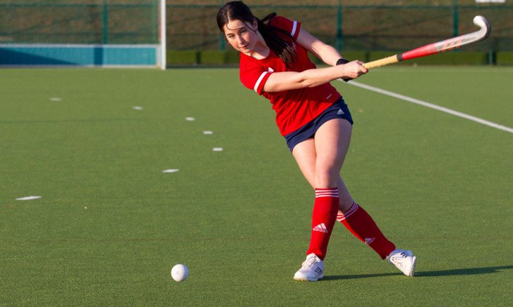  Olivia hitting the ball on the astroturf in Team England Hockey kit 