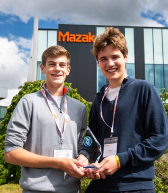  Benji and Miles in front of the Mazak building holding their Technology Design and Innovation Challenge trophy 