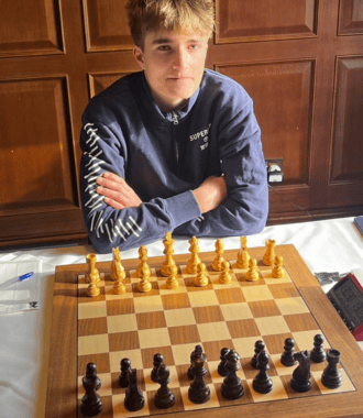  Henry sitting in front of a chess board at the Cambridge International Chess Congress 