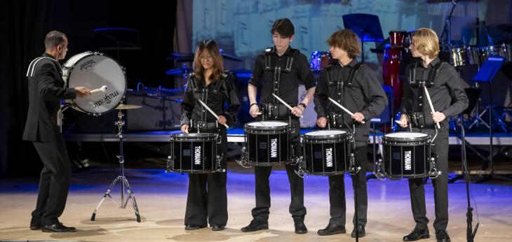  Pupils on stage playing the drums as a percussion group performing on stage in the Film Concert 