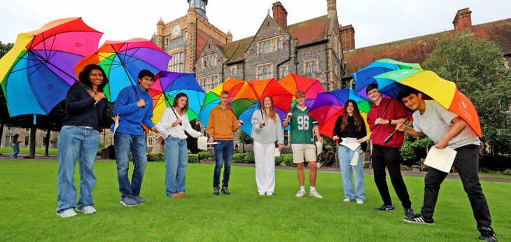  Pupils in the Quad celebrating their results on GCSE Results Day standing under rainbow umbrellas 