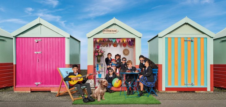  Prep School pupils playing together in a beach hut on Brighton seafront on a sunny day 