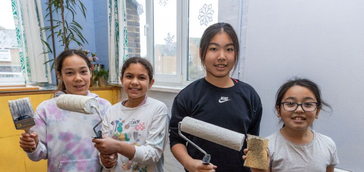  Prep School pupils holding paint brushes to paint a room as part of Make A Difference Day 