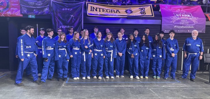  Pupils in blue boiler suits on the stage at a Robotics competition 