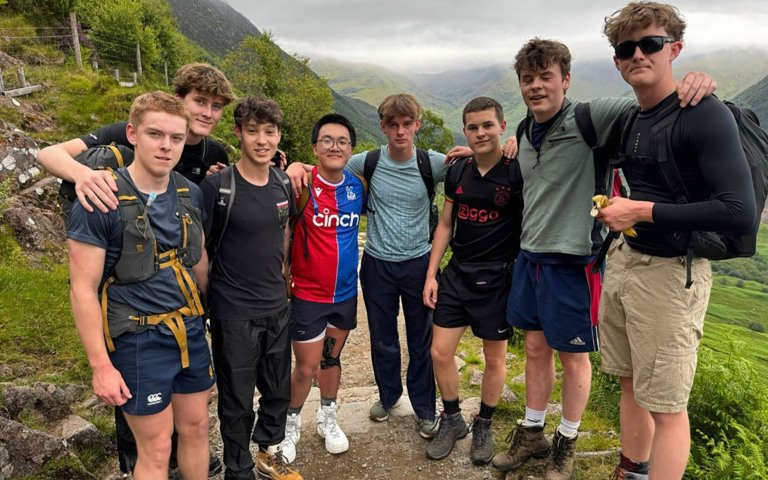  Pupils stopping for a break whilst completing the Three Peaks Challenge with their arms around each other 