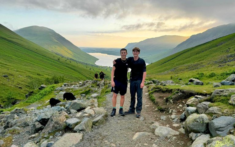  Pupils undertaking the Three Peaks Challenge as the sun is setting with their arms around each other 