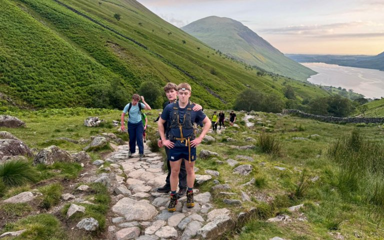  Pupils climbing up Ben Nevis to raise money for charity with a beautiful view of a lake in the background for Three Peaks Challenge 