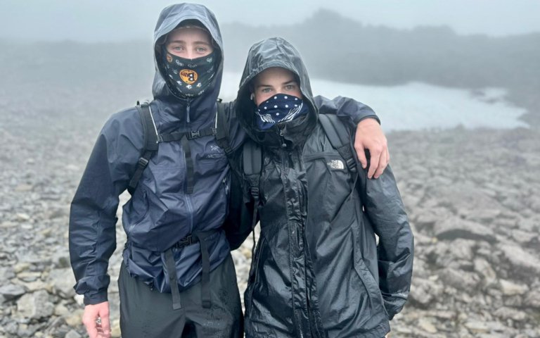  Pupils in waterproofs with balaclavas with their arms round each other at the top of Snowdonia as part of the Three Peaks Challenge 