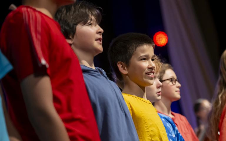  Lower School pupils in brightly coloured t-shirts singing on stage at the Film Concert 