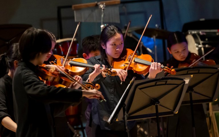  Pupils playing string instruments on stage at the Film Concert 