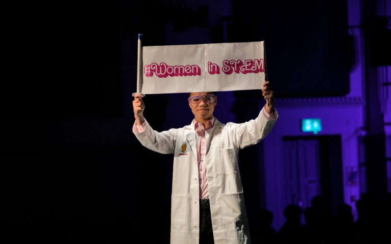  Pupil in a Barbie inspired catwalk in a lab coat holding a #women in STEM sign at the Fenwick Fashion Show for charity 