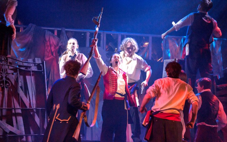  Pupils playing revolutionaries in the production of Les Misérables holding up rifles in a barricade 