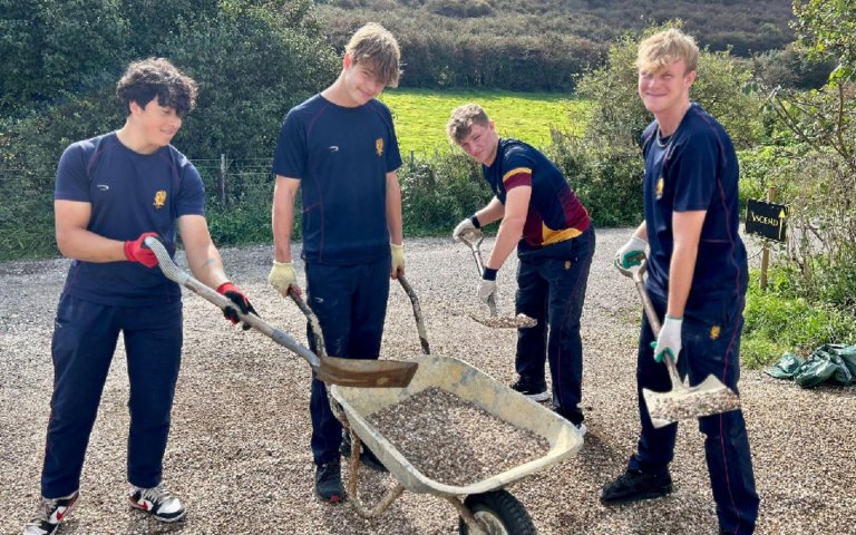  Pupils with shovels and a wheelbarrow shovelling gravel on Make A Difference Day 