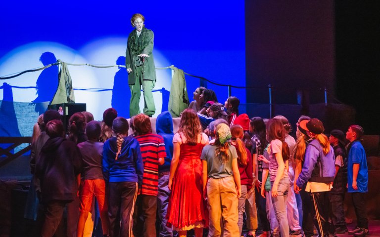  Pupil playing Bill Sykes performing from a platform whilst the rest of the cast watch 