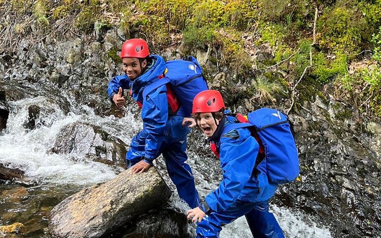  Prep School pupils hiking up rocks next to a river on a trip to Snowdonia 