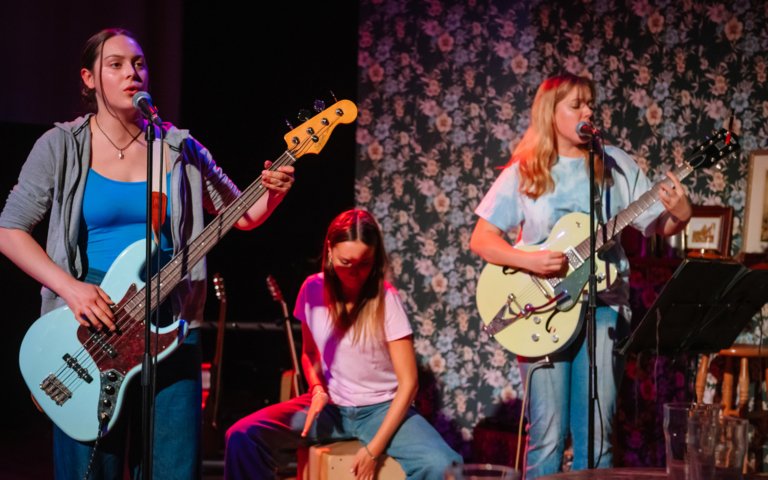  Pupils playing the electric guitar and singing into a microphone on stage in the production of Two 