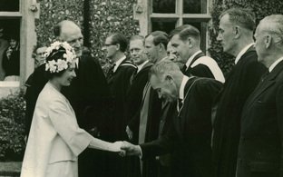 Queen Elizabeth shaking hands with staff members in a black and white photo from the archives