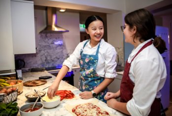 Boarders making homemade pizzas together in the evening in the kitchen in their Boarding house