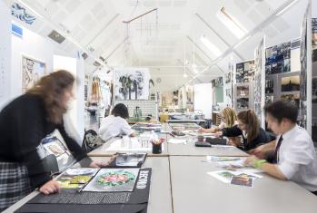 GCSE Art pupils sitting at tables in the Art Room working on their coursework