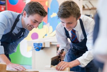 Pupil using a saw being supervised by a teacher in a Design and Technology lesson