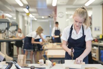 4th Form pupil sawing a block of wood in a DT lesson