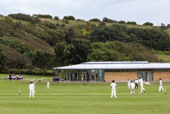 Pupils playing a Cricket fixture on the Jubilee Ground in front of the Pavilion