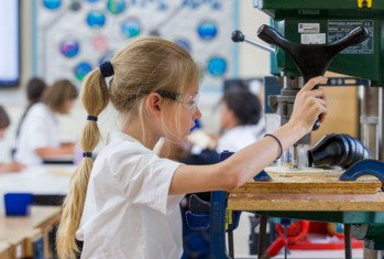 Pupil concentrating on sawing a piece of wood with a bandsaw in a DT lesson