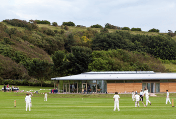 Pupils playing Cricket on the Jubilee Ground in front of the Pavilion with the South Downs in the background