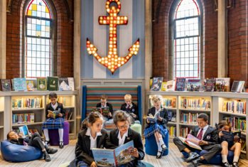 Prep School pupils sitting on beanbags in the library reading books amongst the book shelves