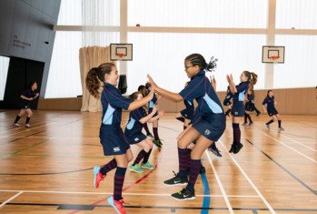 Prep School pupils jumping to high five each other at a Games session in the NASH in the SSS