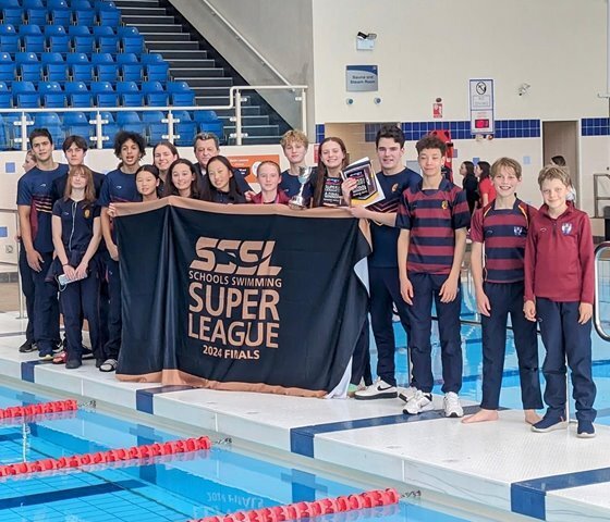  Pupils standing by the pool holding a banner at the Schools Swimming Super League Finals 