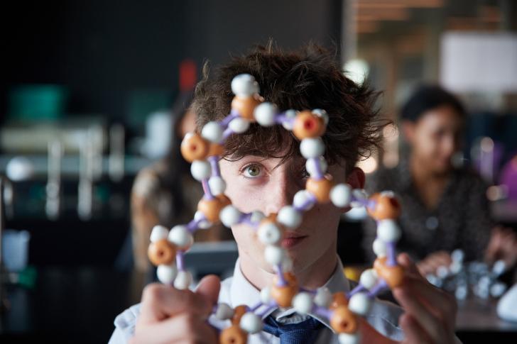  A-Level pupil examining a model of a molecular structure in a Chemistry lesson 