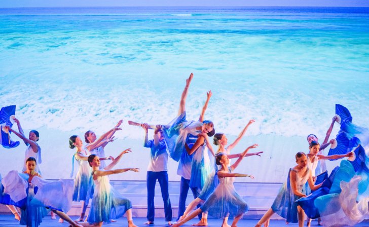  Pupils in flowy outfits performing a sea themed dance on stage 