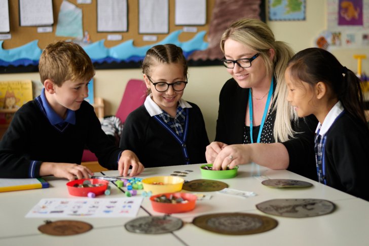  Pre-Prep pupils enjoying learning about money in the classroom with the assistance of their teacher 